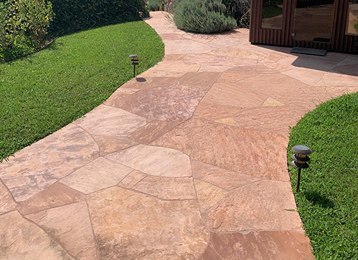 flagstone pathway curving through artificial turf landscape