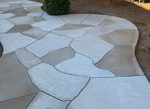 flagstone pathway curving through artificial turf landscape